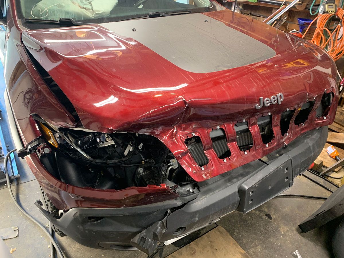 Before: damaged red Jeep Cherokee with front-end collision damage